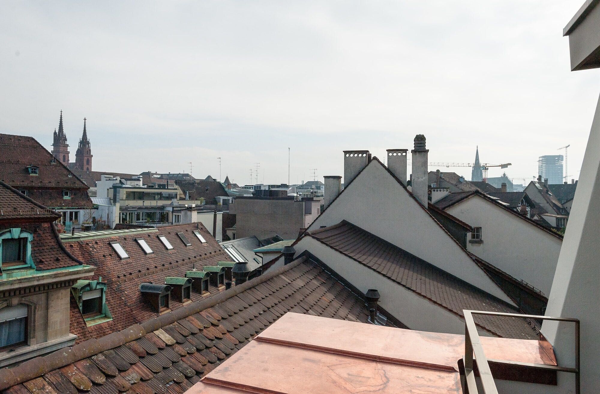 A view of a cityscape with various buildings, including a church tower and modern structures.
