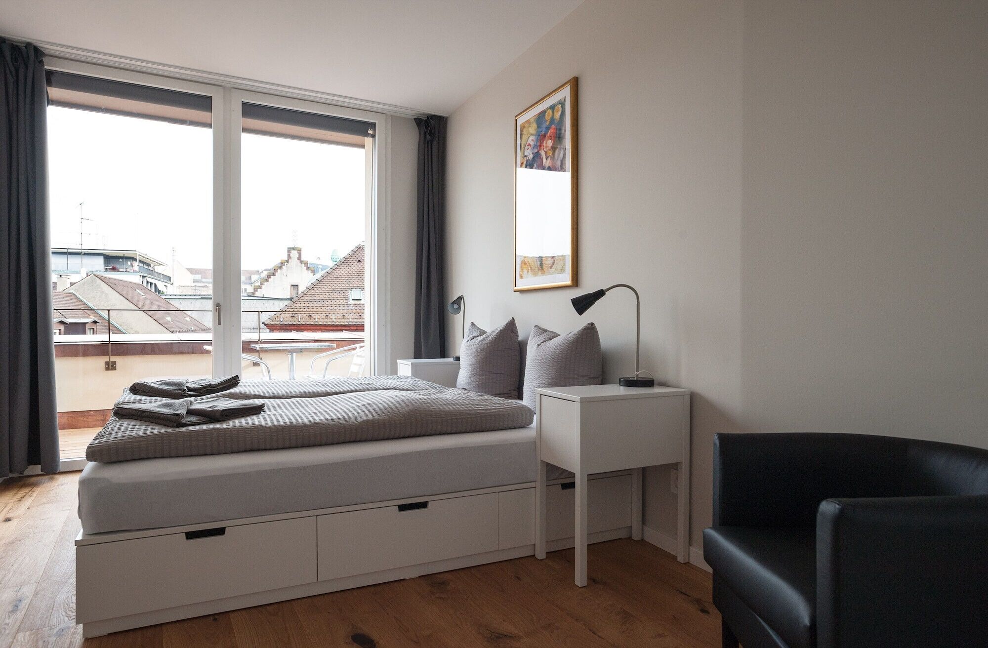 A bedroom with a bed, bedside table, lamp, and a chair.