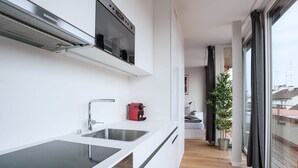 Ett modernt kök med en inbyggd ugn, en kaffemaskin och ett stort fönster.