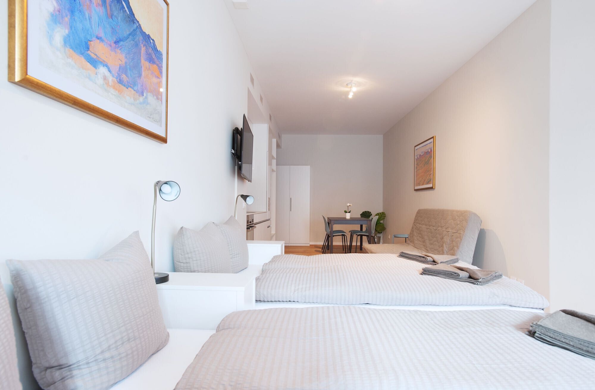 Una habitació moderna i ben il·luminada amb dos llits, un escriptori i una cadira.