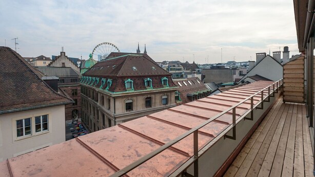 En takterrass med utsikt över de omgivande byggnaderna och ett pariserhjul i fjärran.