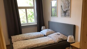 Una cama con una colcha estampada, una mesita de noche con una lámpara y dos cuadros enmarcados en la pared.
