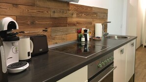Una cocina moderna con protector contra salpicaduras de madera, estufa integrada, un lavamanos y una encimera con varios electrodomésticos.
