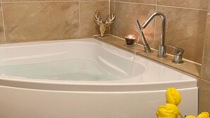 Un baño con una bañera, un grifo y una vela sobre el mueble.