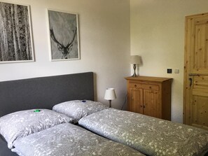 Ein Schlafzimmer mit einem großen Bett, zwei Kissen, einem Holzschrank, einer Lampe und zwei gerahmten Bildern an der Wand.