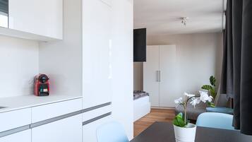 A modern, minimalist room with a dining area, a small kitchenette, and a bed.