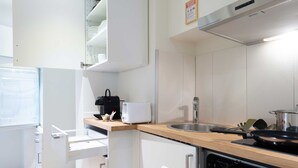 A modern kitchen with white cabinets, a wooden countertop, a built-in oven, and a stainless steel sink. - Hitrental Old Town Apartments (Lucerne)