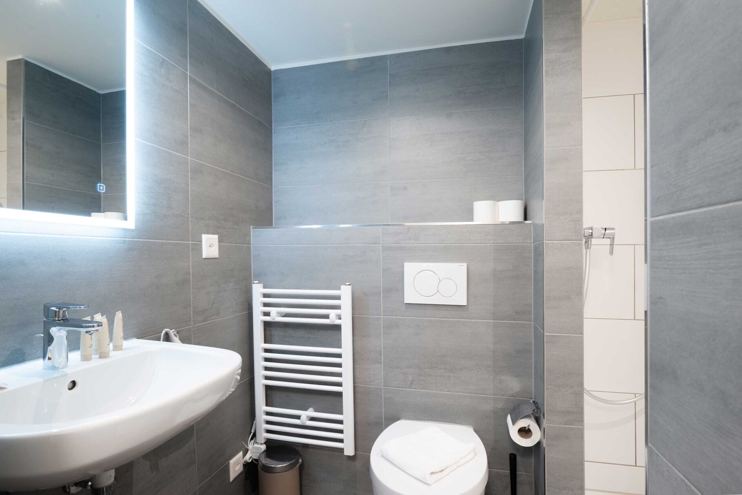 A modern bathroom with a white sink, toilet, and towel rack.
