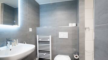 A modern bathroom with a white sink, toilet, and towel rack.