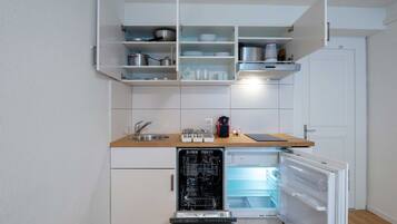 A compact kitchen with white cabinetry, a dishwasher, and a built-in refrigerator.