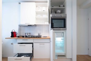 Uma cozinha compacta com forno embutido, geladeira e um pequeno balcão.