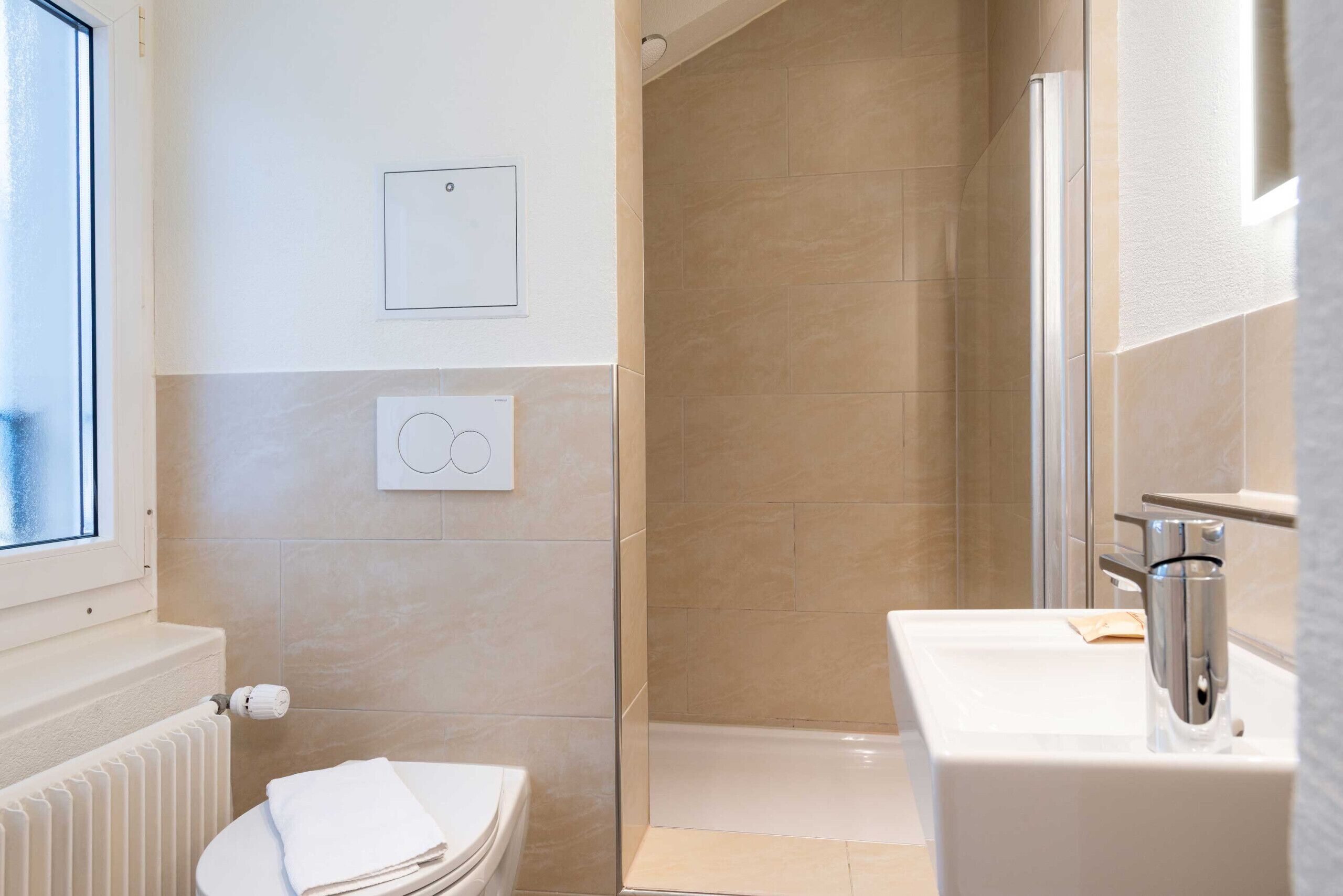 A bathroom with a toilet, a shower, a sink, and a window.