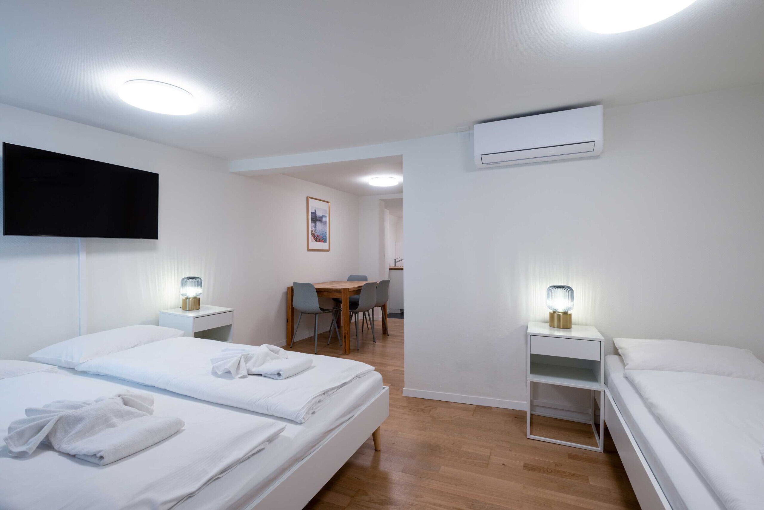 Une chambre d’hôtel avec deux lits, un bureau, une chaise, une télévision et un appareil de climatisation.