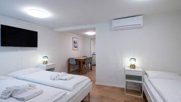 Une chambre d’hôtel avec deux lits, un bureau, une chaise, une télévision et un appareil de climatisation.