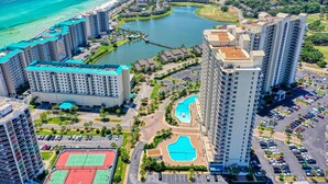 A high-rise hotel with multiple floors, a central courtyard with a swimming pool, and a beach view.