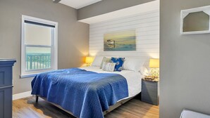 A bedroom with a bed, a window, a ceiling fan, and a painting on the wall.