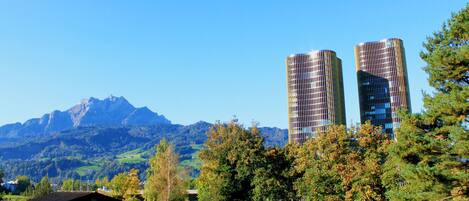 A modern building with a unique architectural design, surrounded by a lush green landscape and mountains in the background.