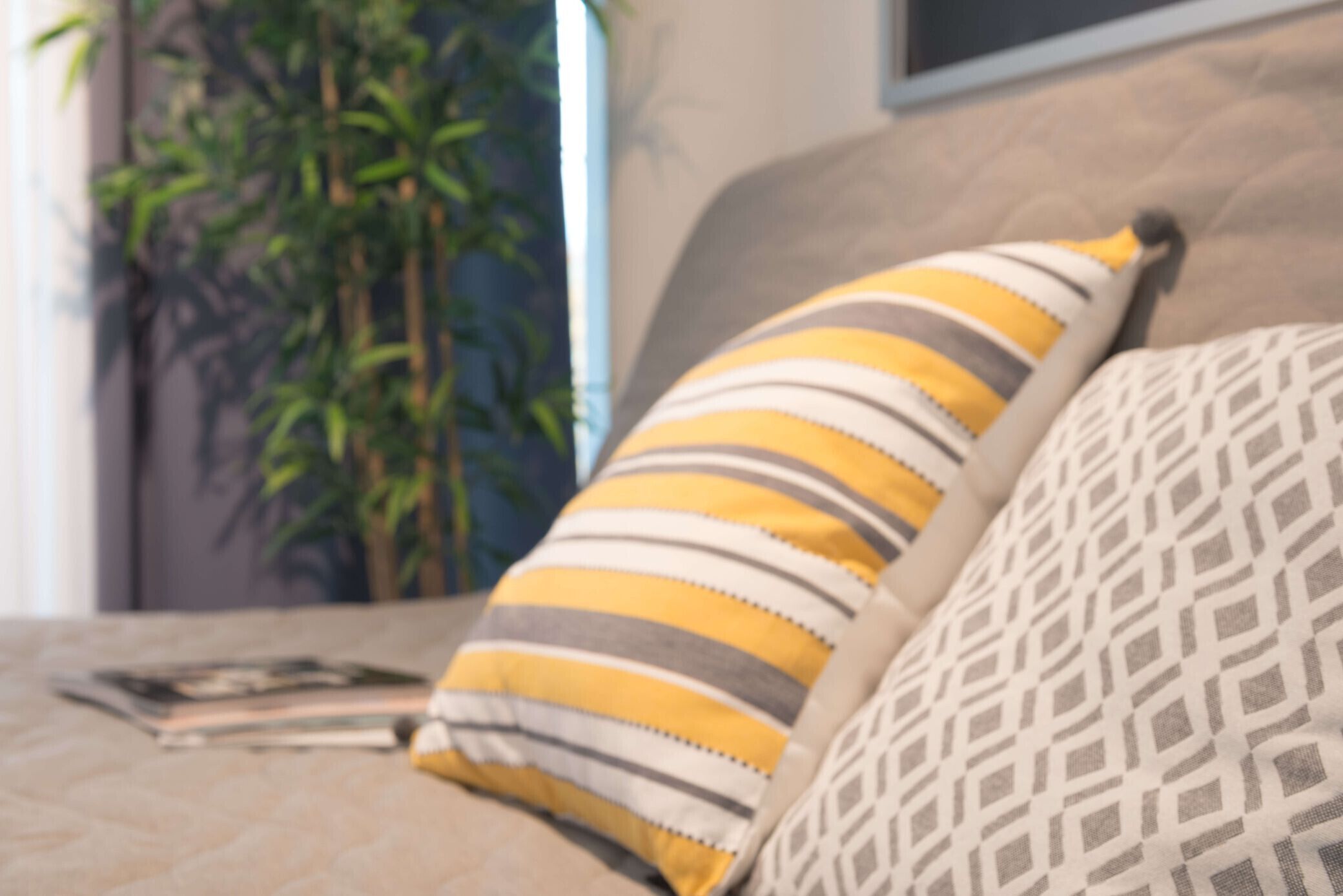 Ein Bett mit zwei Kissen, eines gestreift, das andere mit geometrischem Muster.
