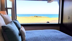 A bedroom with a large window offering a view of the beach and ocean. - Star House Lodge - Ocean Front Timbered Lodge (Fort bragg)