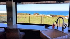 A kitchen with a view of the ocean, a sink, and a bottle of soap. - Star House Lodge - Ocean Front Timbered Lodge (Fort bragg)