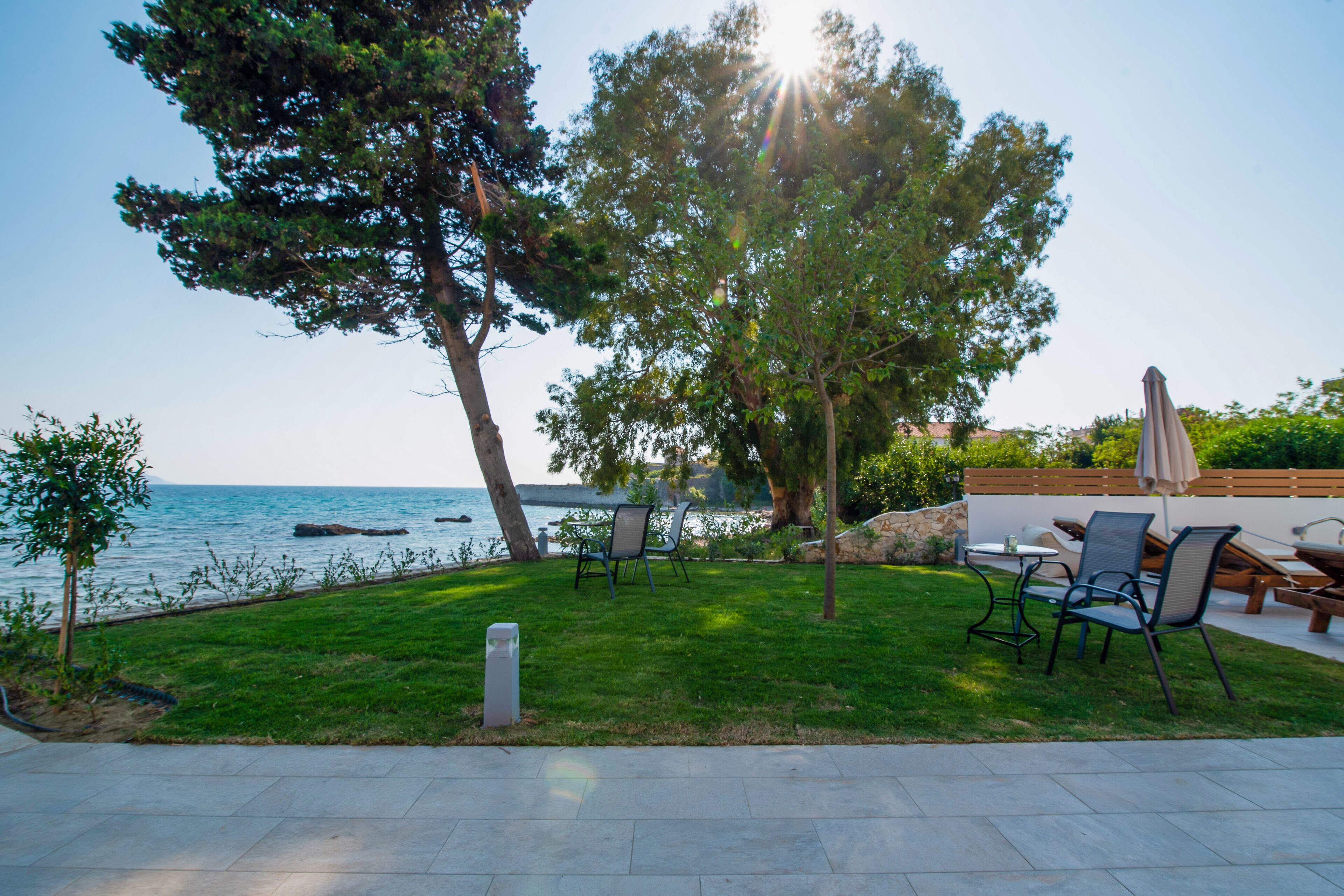 A patio with outdoor furniture, a view of the sea, and a tree.