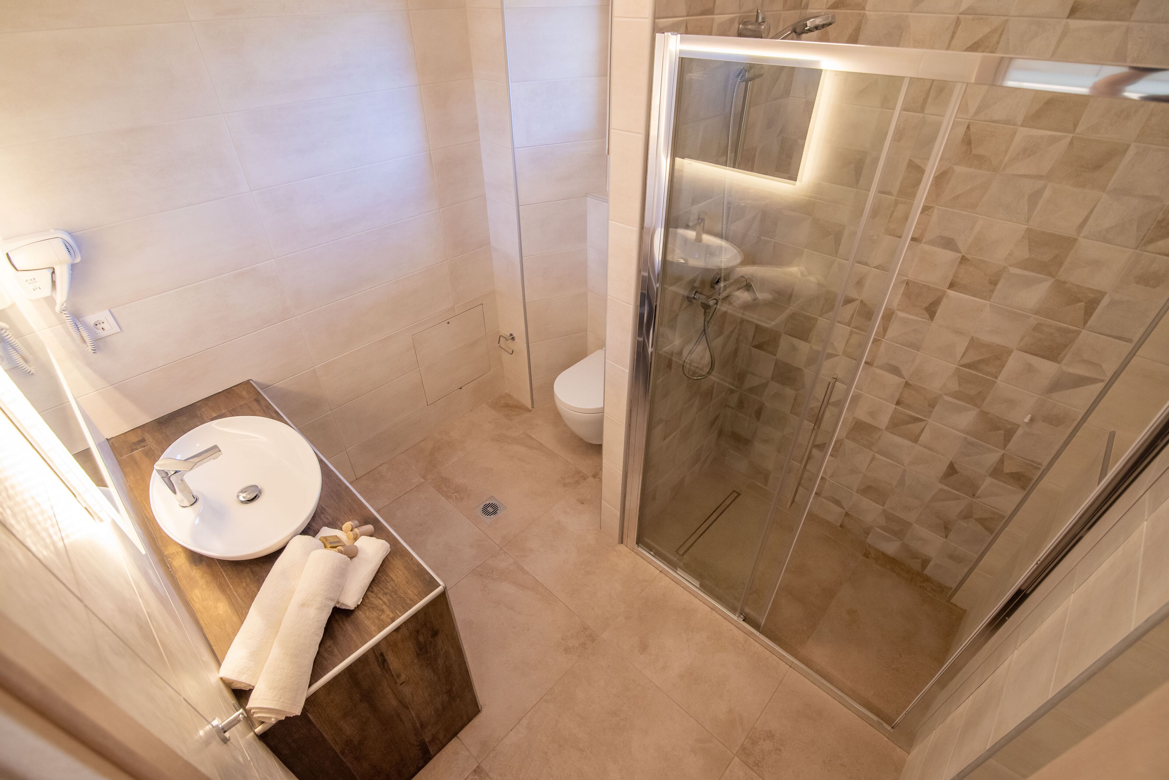 Une salle de bain moderne avec une douche à parois de verre, un meuble-lavabo en bois et des toilettes.