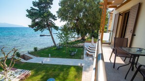 Un patio con mobiliario exterior, vista al mar y un sendero de piedra que lleva a una zona ajardinada.