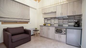 A compact kitchen with a built-in oven, a coffee maker, and a small side table with a plant.