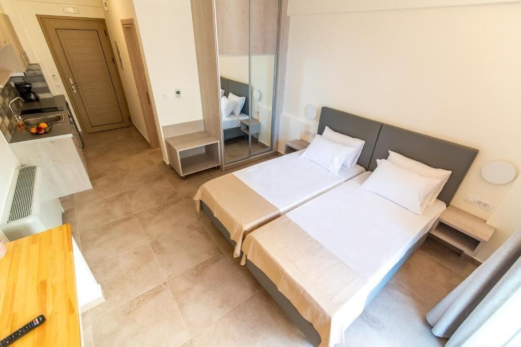 Una habitación de hotel con cama, mesitas de noche, escritorio y espejo.