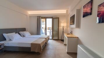 A hotel room with two beds, a desk, a chair, a radiator, and a view of the outside balcony.