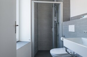 Un baño moderno con ducha envuelta en vidrio, inodoro blanco y bañera.
