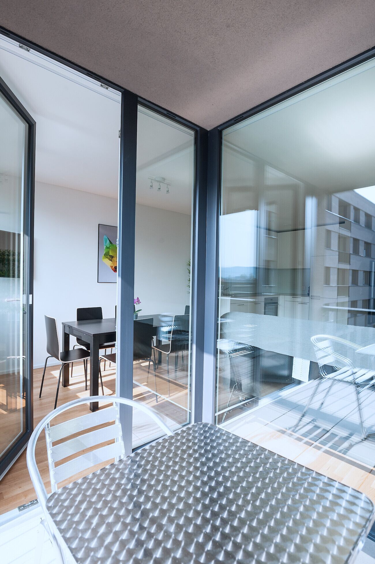 A modern interior with a dining area, a large window, and a view of a building outside.