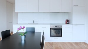 Eine moderne Küche mit weißen Schränken, einem schwarzen Esstisch und einem kleinen Blumentopf.