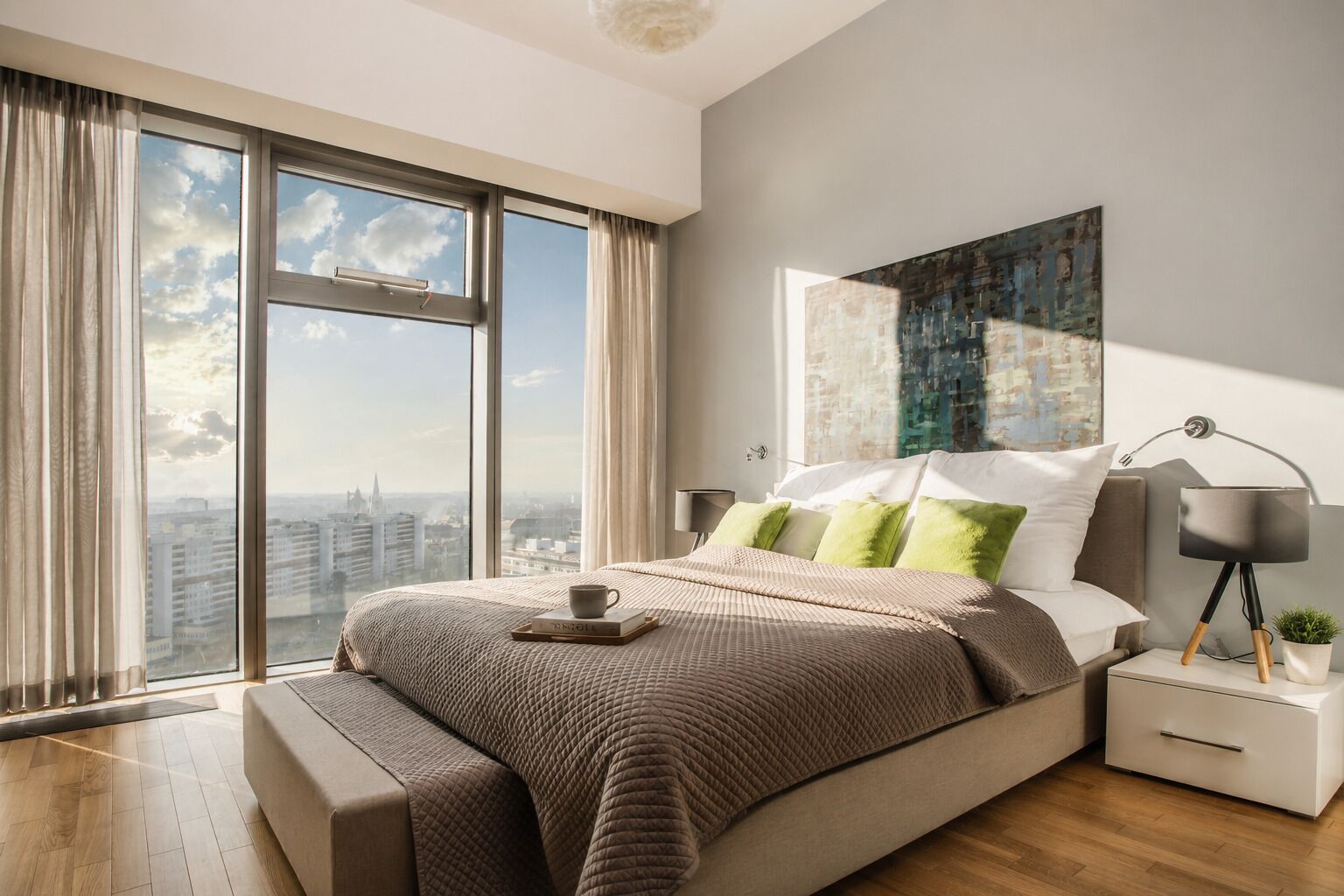 Una camera da letto moderna con un letto grande, un comodino con una lampada e vista sulla città attraverso ampie finestre.