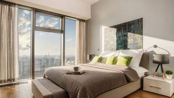 Una camera da letto moderna con un letto grande, un comodino con una lampada e vista sulla città attraverso ampie finestre.
