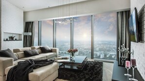 Een moderne woonkamer met een groot raam, een bank, een salontafel en een tv aan de muur.