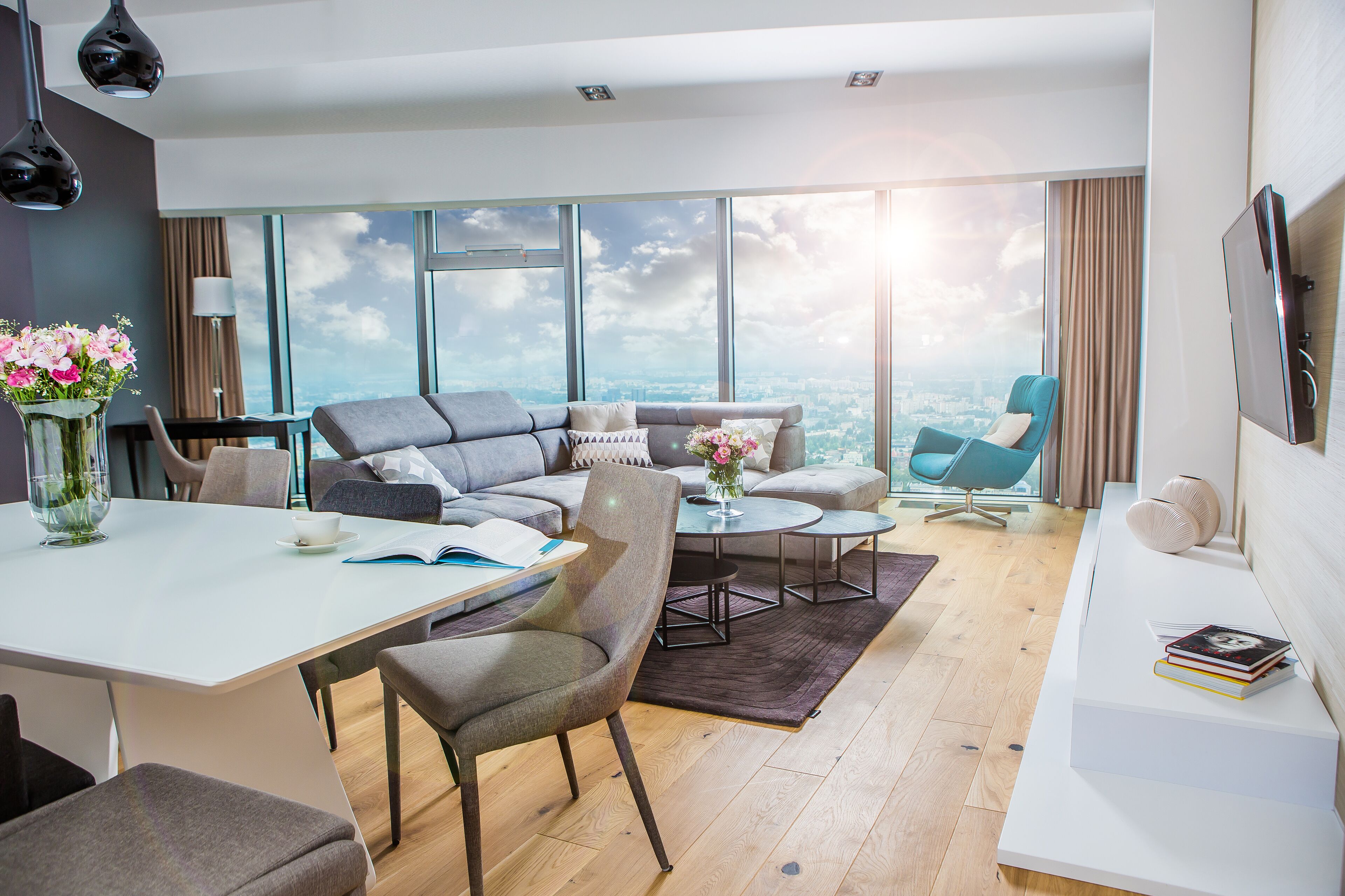 A modern living room with a large window, a sofa set, a coffee table, and a TV.