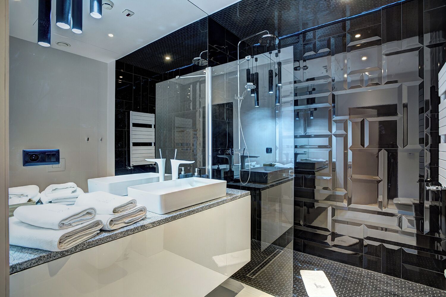 Un baño moderno con ducha envuelta en vidrio, un espejo grande y un lavamanos doble.