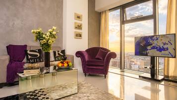 A modern living room with a sofa, armchair, coffee table, and a large window with a city view.