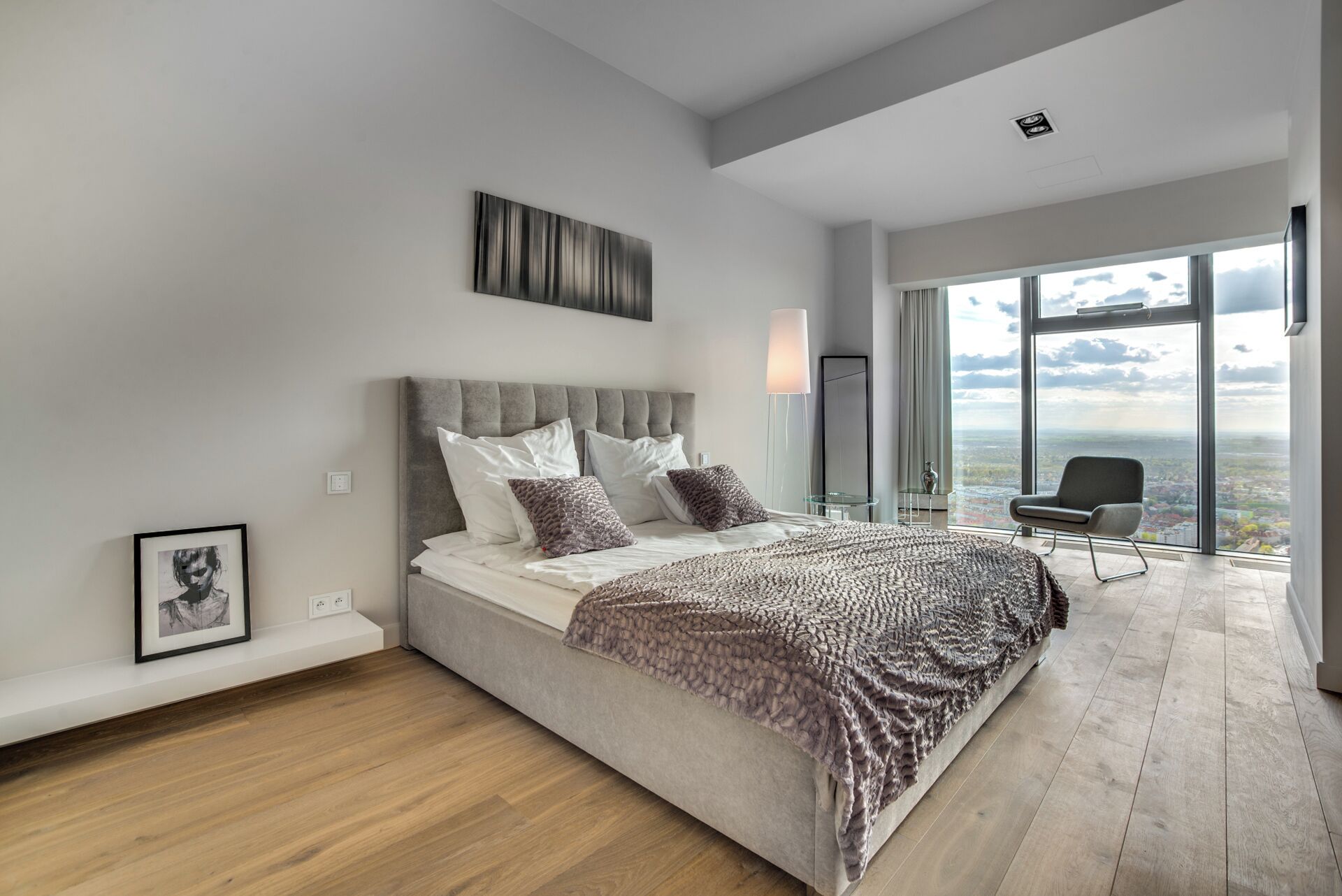 A modern bedroom with a large bed, a city view, and a minimalist design.
