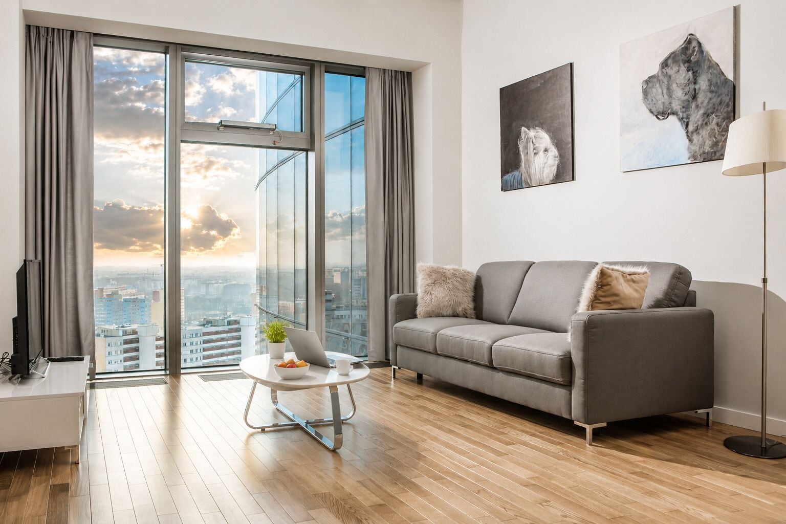 Ein modernes Wohnzimmer mit einer Couch, einem Couchtisch und Blick auf die Stadt durch große Fenster.