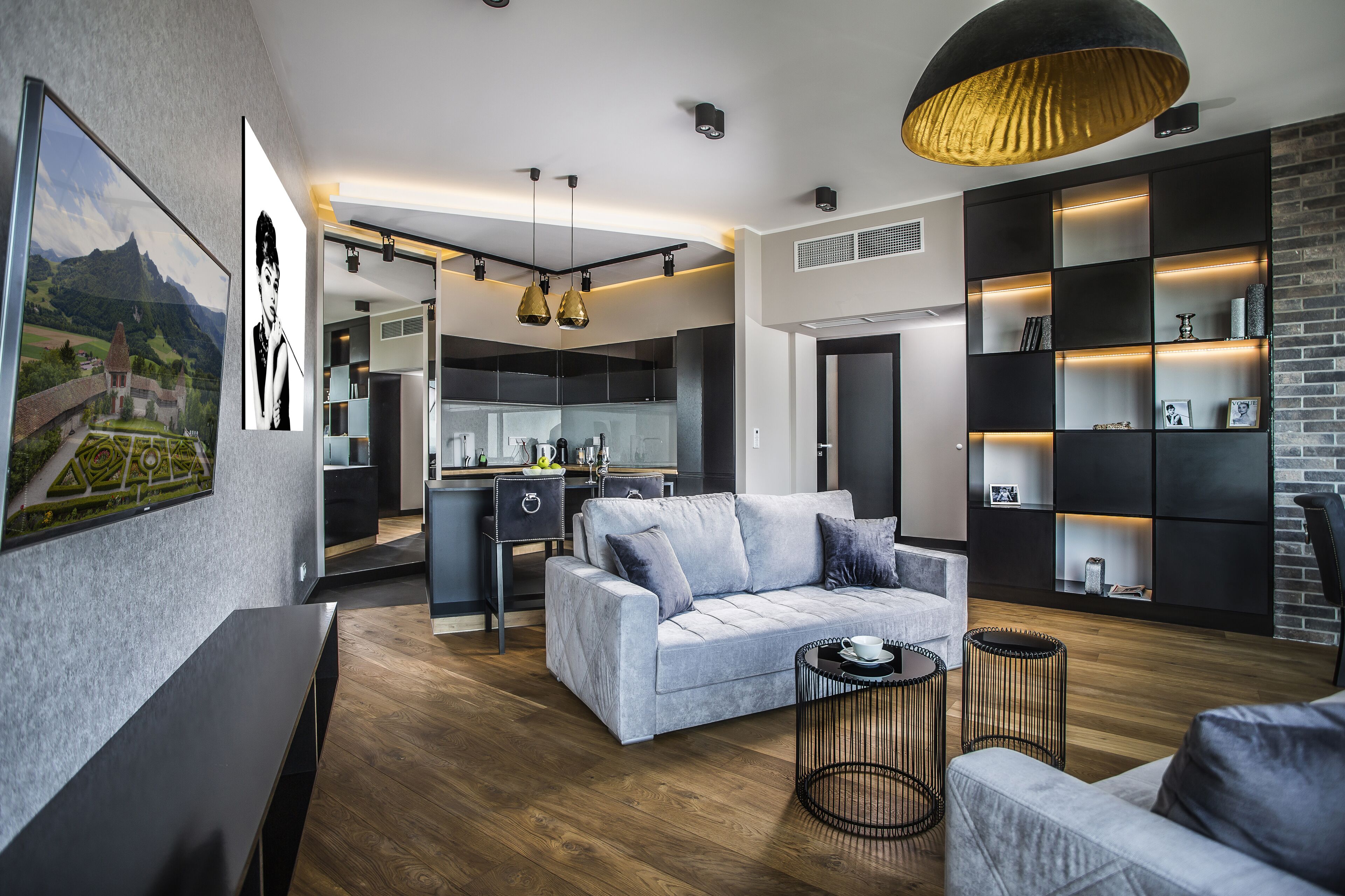 A modern living room with a grey sofa, a coffee table, and a dining area with a kitchen in the background.