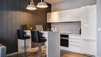 A modern kitchen with white cabinets, a central island with bar stools, and pendant lighting.