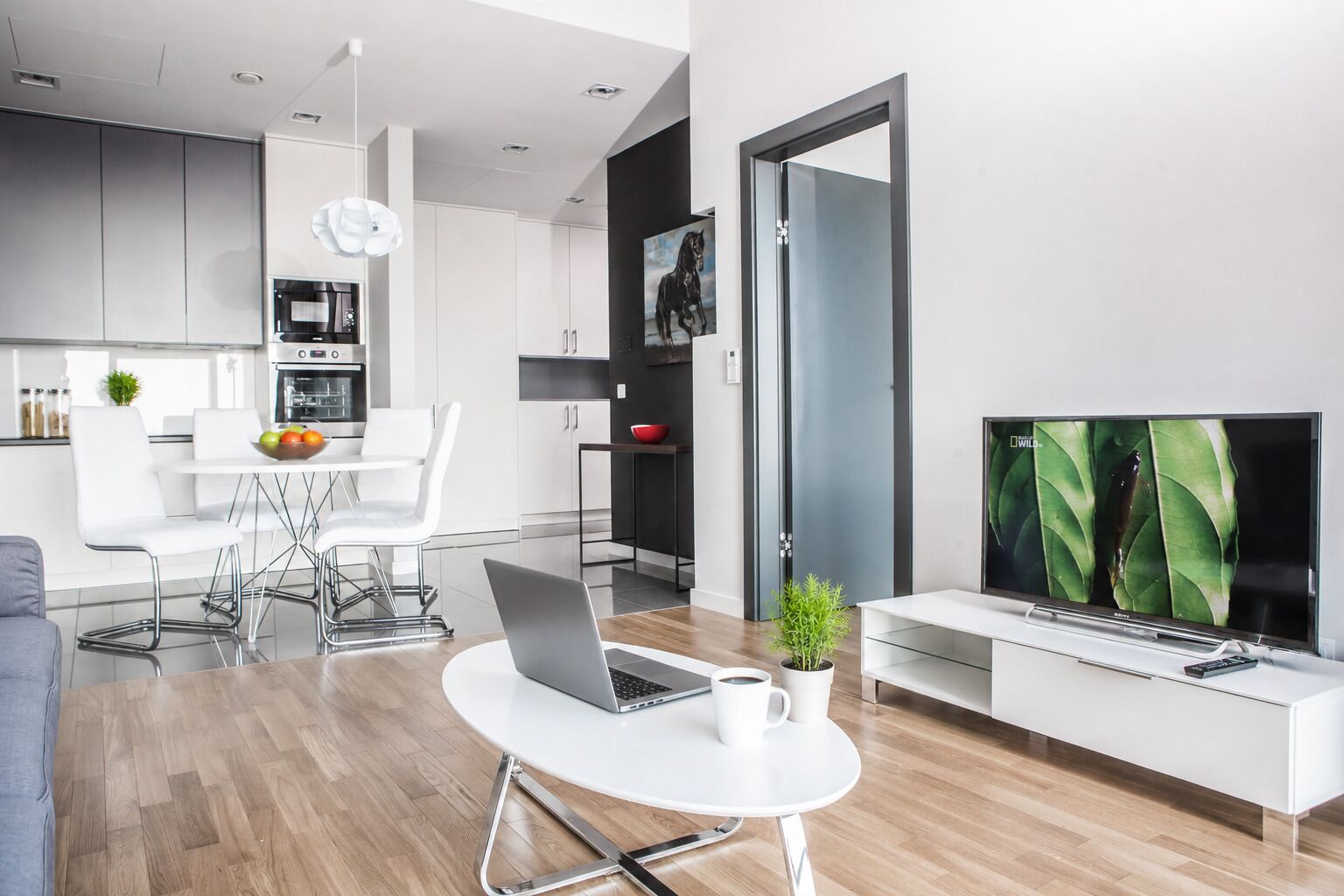 Un soggiorno moderno con zona pranzo, cucina e TV.