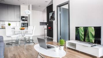 A modern living room with a dining area, a kitchen, and a TV.