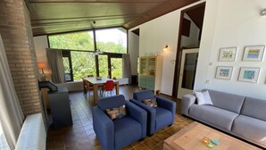 Amplia sala de estar con mesa de comedor, sofás azules, un sofá gris y una mesa de centro de madera.