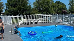A swimming pool with inflatable rings and a white fence. - Sunset On The Water! (Port Clinton)