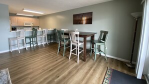 A modern kitchen with white cabinets, a wooden dining table, and teal chairs. - Sunset On The Water! (Port Clinton)
