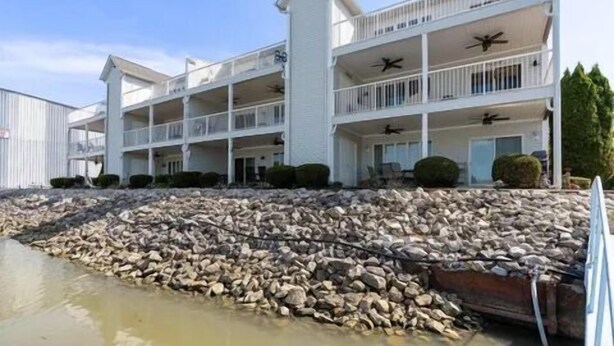 A multi-story hotel with balconies and a rocky shoreline. - Sunset On The Water! (Port Clinton)