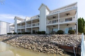 A multi-story hotel with balconies and a rocky shoreline. - Sunset On The Water! (Port Clinton)